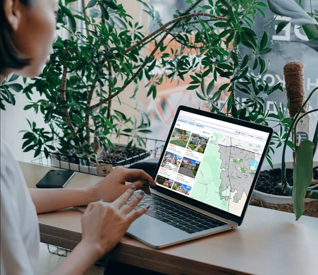 A woman using a laptop with listings on the screen