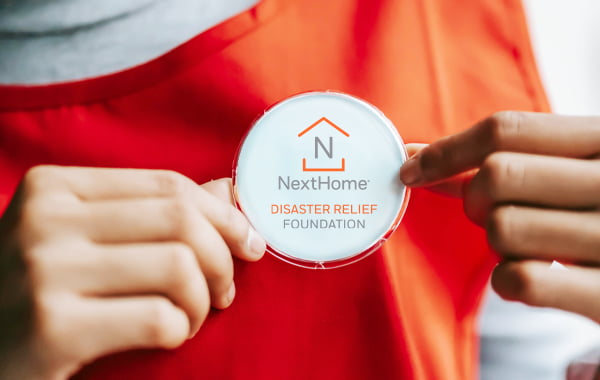Close-up of a woman holding a NextHome Disaster Relief Foundation button