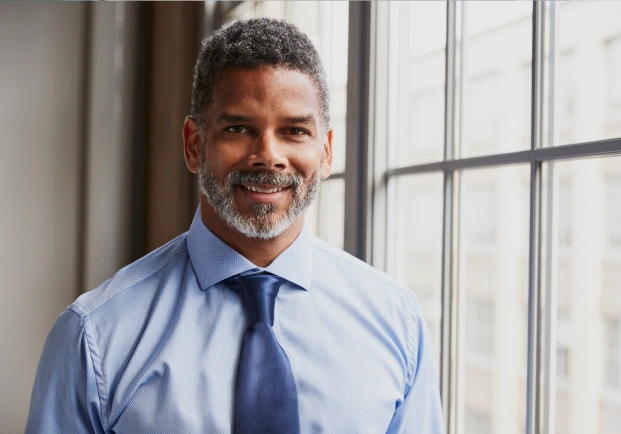 A person looking directly in the camera with a button up and tie.